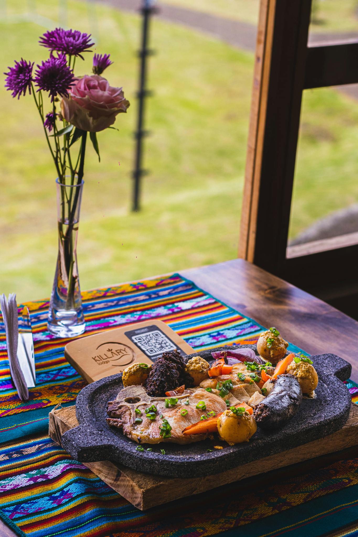 A traditional Peruvian dish served on a vibrant table with a flower vase by the window.